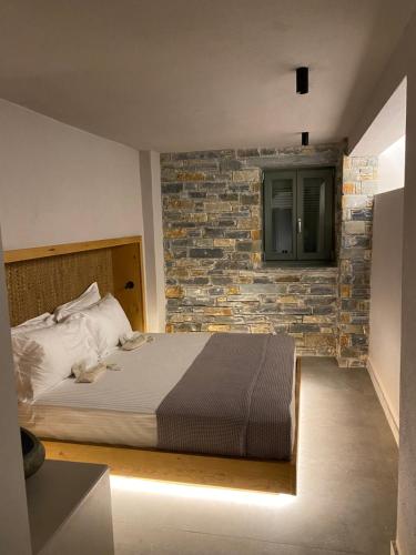 a bedroom with a bed and a brick wall at EJ Boutique Suites in Milína