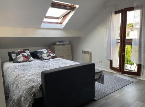 1 dormitorio con 1 cama, tragaluz y ventana en Appartement spacieux proche de paris en Carrières-sur-Seine