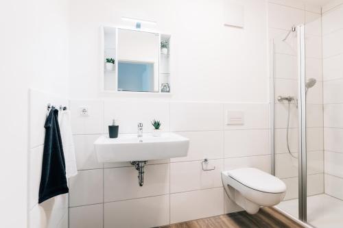 Urban City Lifestyle Appartement في بيليفيلد: حمام أبيض مع حوض ومرحاض