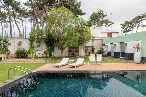 a swimming pool with lounge chairs next to a house at Casa Atlântico in Colares