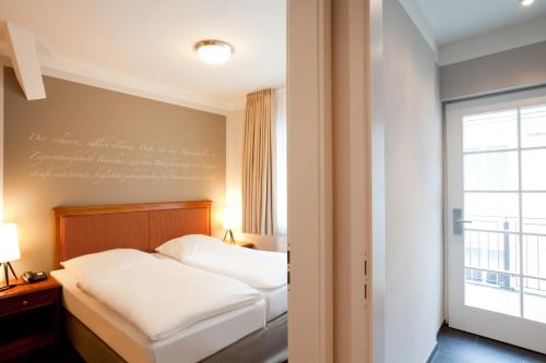 a hotel room with a bed and a window at Batschari Palais Baden-Baden in Baden-Baden