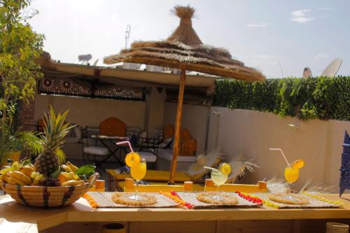 een tafel met wat drankjes en een rieten paraplu bij Riad Les Gazelles D'Orient Marrakech in Marrakesh