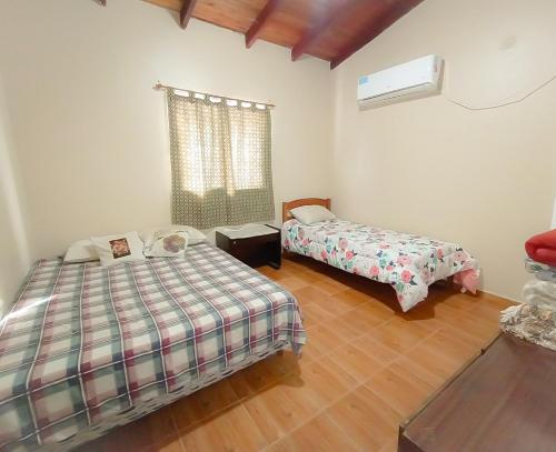 a bedroom with two beds and a window and wooden floors at Bungalows La Pilarica in Federación