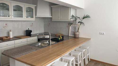 a kitchen with white cabinets and a wooden counter top at Puro São Jacinto in Aveiro