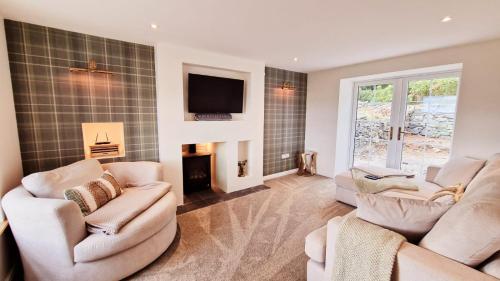 a living room with two couches and a fireplace at Nordlys Cottage in Newton Stewart