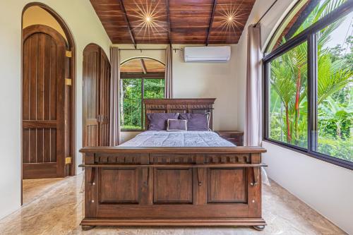 a bedroom with a wooden bed and a large window at Las Palomas Villas Of Uvita in Uvita