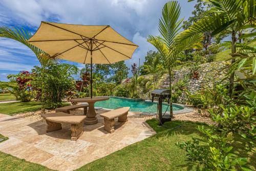 a pool with a picnic table and an umbrella at The Garden Villas by Vista Celestial in Uvita