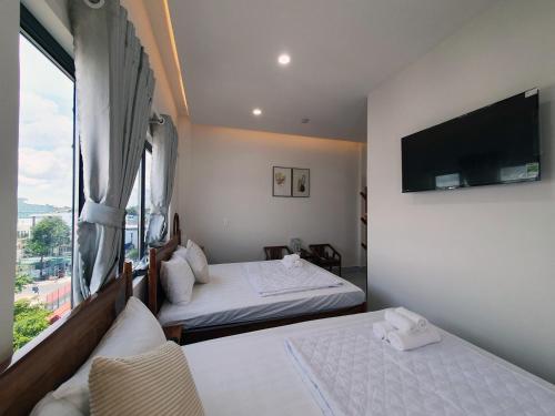 a hotel room with two beds and a large window at Hero Hostel & Billiards in Chau Doc