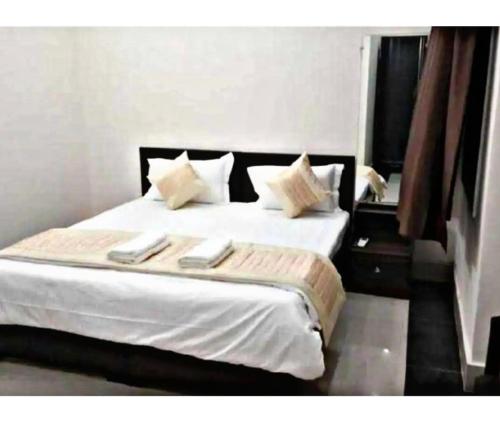 1 dormitorio con 1 cama con sábanas y almohadas blancas en Hotel namo, en Alwar