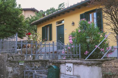 uma casa amarela com uma cerca e flores à frente dela em Casa con giardino in Mugello a 30 minuti da Firenze "SoleLuna" em Osteria di Novoli