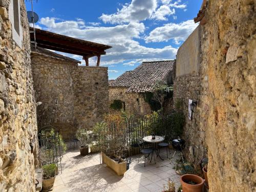 une cour avec une table et des chaises dans un bâtiment en pierre dans l'établissement LA BOULANGERIE, à Saint-Sauveur-de-Cruzières