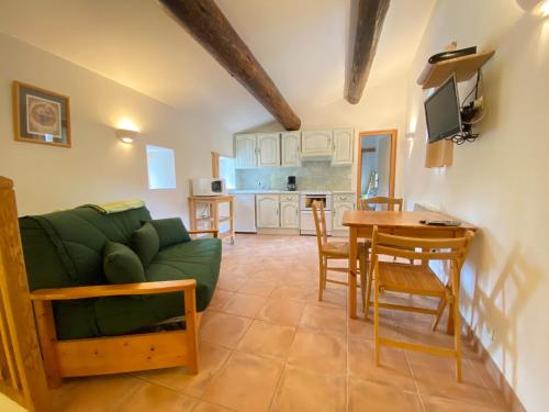 a living room with a green couch and a table at LA BOULANGERIE in Saint-Sauveur-de-Cruzières