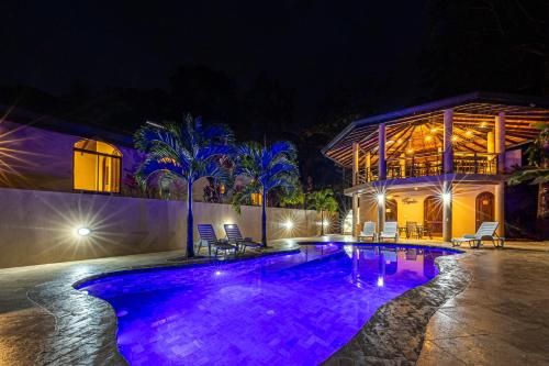 uma piscina à noite com luzes roxas em Las Palomas Villas Of Uvita em Uvita