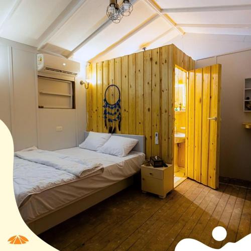 Palapa Resort - El Alamein في العلمين: غرفة نوم بسرير وجدار خشبي