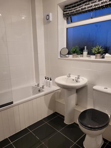 ein Badezimmer mit einem Waschbecken, einem WC und einer Badewanne in der Unterkunft 4 Bedroom House EMA with Parking and Garage in Castle Donington