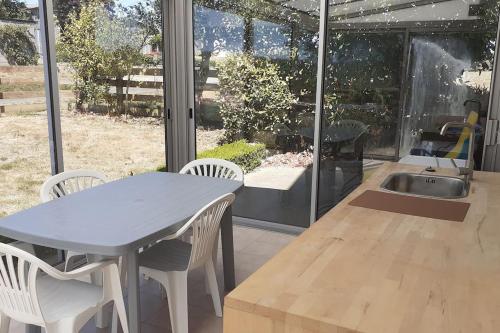 une cuisine avec une table, des chaises et un évier dans l'établissement Maison calme individuelle proche du Mont st Michel, à Saint-Aubin-de-Terregatte