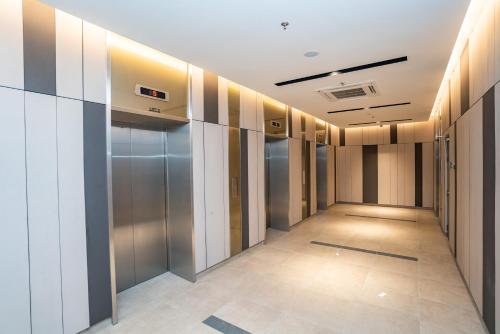 a hallway of a building with glass doors and tile floors at Ipoh Tambun Lost World Sunway Onsen Mina 3R2B 8pax in Tambun