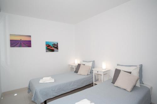 a bedroom with two beds and a table with two lamps at Casa Brillante in Playa de San Juan