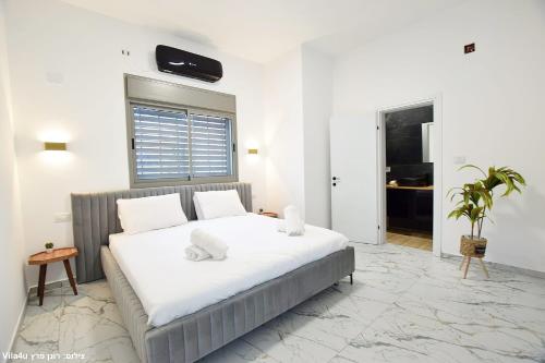 1 dormitorio con 1 cama grande con sábanas blancas en אחוזת אור הנוף, en Shetula