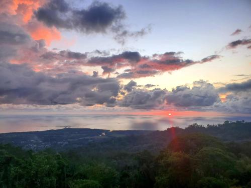 a sunset over a body of water with trees at The Garden Villas by Vista Celestial in Uvita