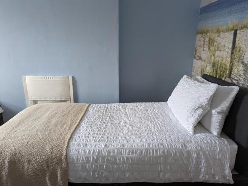 a bedroom with a white bed with a blue wall at Gull Wing Guesthouse in Lowestoft