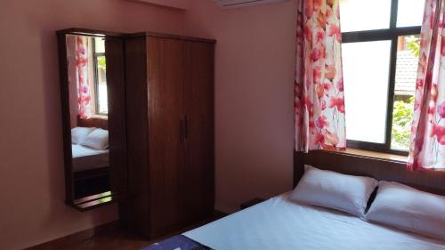 a bedroom with a bed and a cabinet with a mirror at Villa Cleto Guest House in Panaji