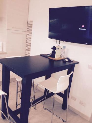 a black desk with two white chairs and a television at Royal Apartment in Ciampino