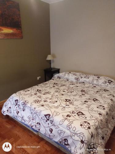 Una cama en un dormitorio con una colcha con flores. en Santa Rosa en Mendoza