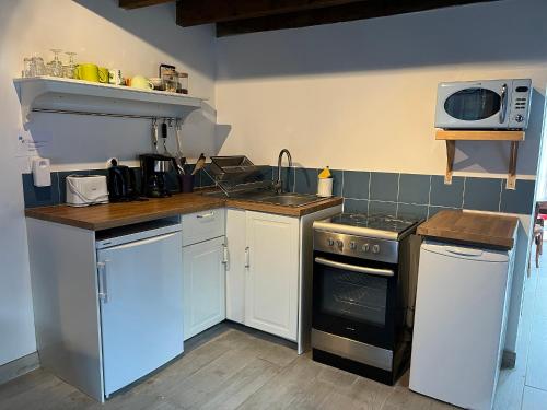 uma cozinha com um fogão e um micro-ondas em Maison independante pour 2 tout inclus Tiny House for 2 all included em Teilhet