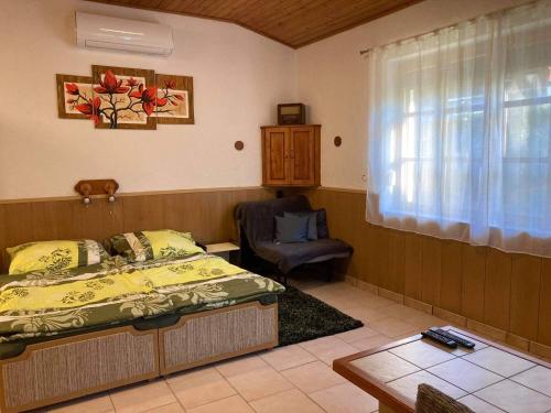 a bedroom with a bed and a chair and a window at Horváth Apartmanház in Szigliget