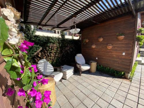 a patio with two chairs and a pergola with purple flowers at Cabañas Tr'eje in Valle de Bravo
