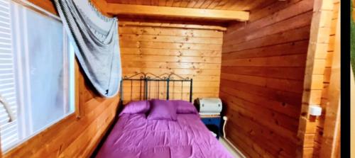 Cette petite chambre en bois comprend un lit violet. dans l'établissement Casa Cuatro-Vientos en Águilas, Murcia, à Águilas