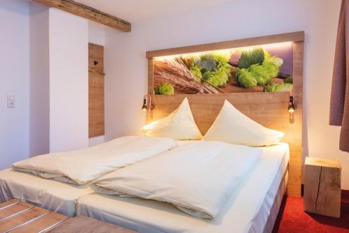 a bedroom with two beds and a painting on the wall at Brauereigasthof Rothenbach in Aufseß