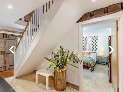 a room with a staircase with a vase of flowers at Luxury Country Cottage With A View in Enstone