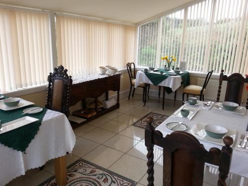 uma sala de jantar com mesas, cadeiras e janelas em Y Garth Luxury Bed and Breakfast em Newport