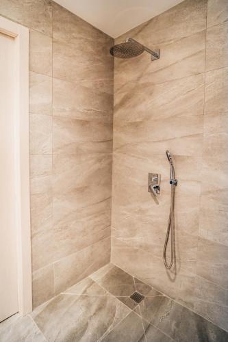 a shower with a shower head in a bathroom at Arevalos Hotel in Cuenca