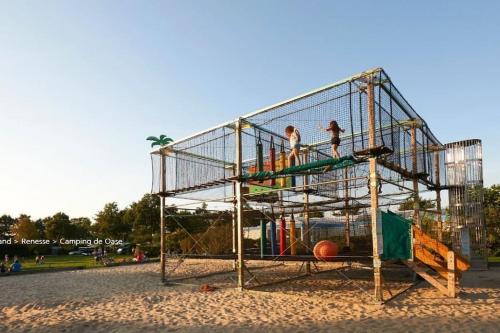 Due persone giocano su una gabbia in un parco giochi di Luxe 4-persoons chalet zon zee strand Renesse. a Renesse