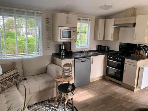 een woonkamer met een bank en een keuken bij Luxe 4-persoons chalet zon zee strand Renesse. in Renesse