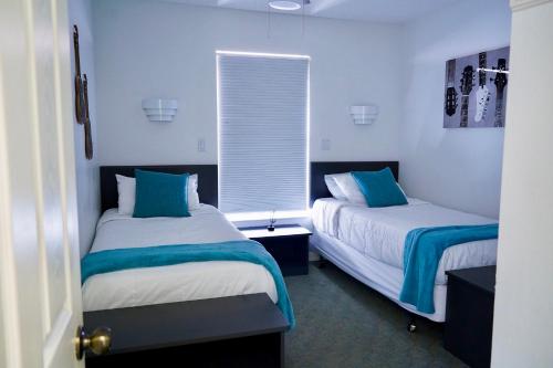 duas camas num quarto com azul e branco em Enchanting Escape 3 Bedroom Minutes from Disney! em Kissimmee