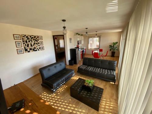 a living room with a black leather couch and a table at Cabañas Tr'eje in Valle de Bravo