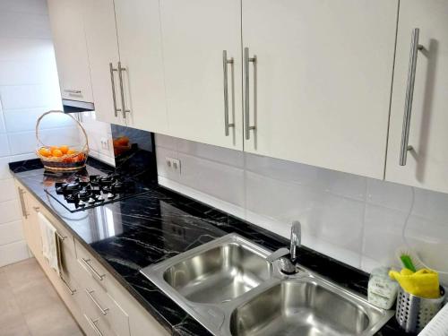 a kitchen with a stainless steel sink and white cabinets at FirstLine BeachView in El Campello