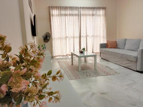 a living room with a couch and a table at Rafflesia Two Bedroom Pool View in Kampong Tanah Merah