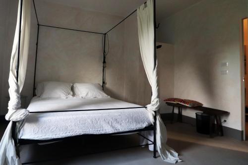 a bedroom with a canopy bed with white sheets at B&B Tricudai in Agliano Terme