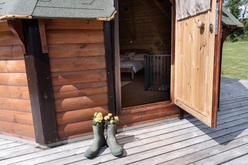 a wooden cabin with a pair of boots on the porch at Exmoor Eco-Pod - Oak Tree Lane in Okehampton