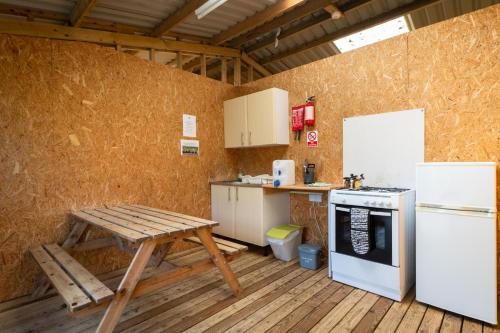 a kitchen with a table and a stove and refrigerator at Exmoor Eco-Pod - Oak Tree Lane in Okehampton