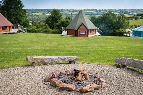 a fire pit in a yard with two benches at Exmoor Eco-Pod - Oak Tree Lane in Okehampton
