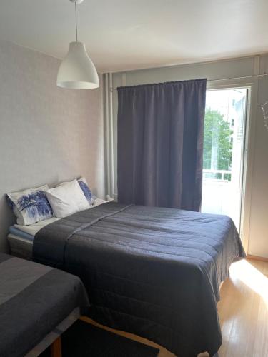 a bedroom with a bed with a blue blanket and a window at City apartment Pikkuvuori in Turku