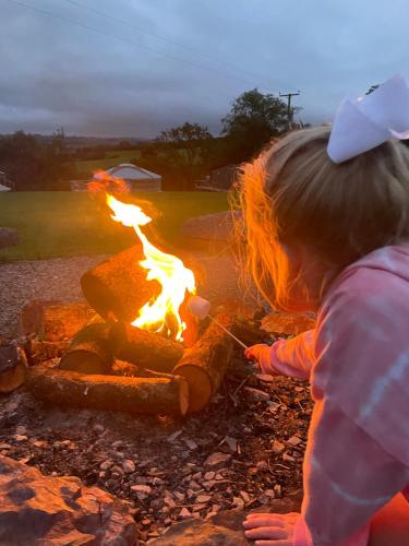 a little girl is playing with a fire at Exmoor Eco-Pod - Oak Tree Lane in Okehampton