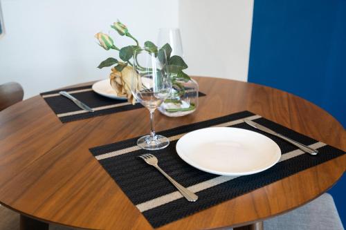 a wooden table with two plates and a wine glass at Feliz en Vista New Duplex 2br Highclass in Ho Chi Minh City