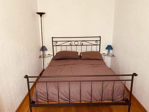 a bedroom with a bed with a metal frame and two lamps at Pretty flat 2mn from beach in Nice